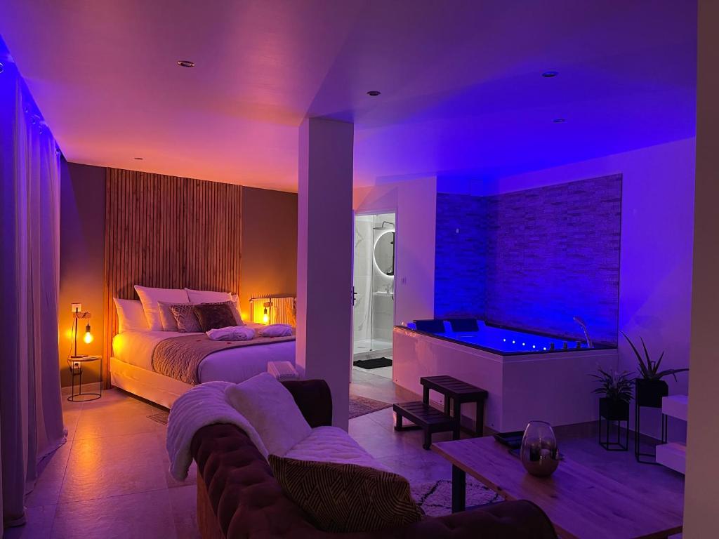 a bedroom with a bed and a tub with purple lights at Appart&amp;Spa Devosge in Dijon