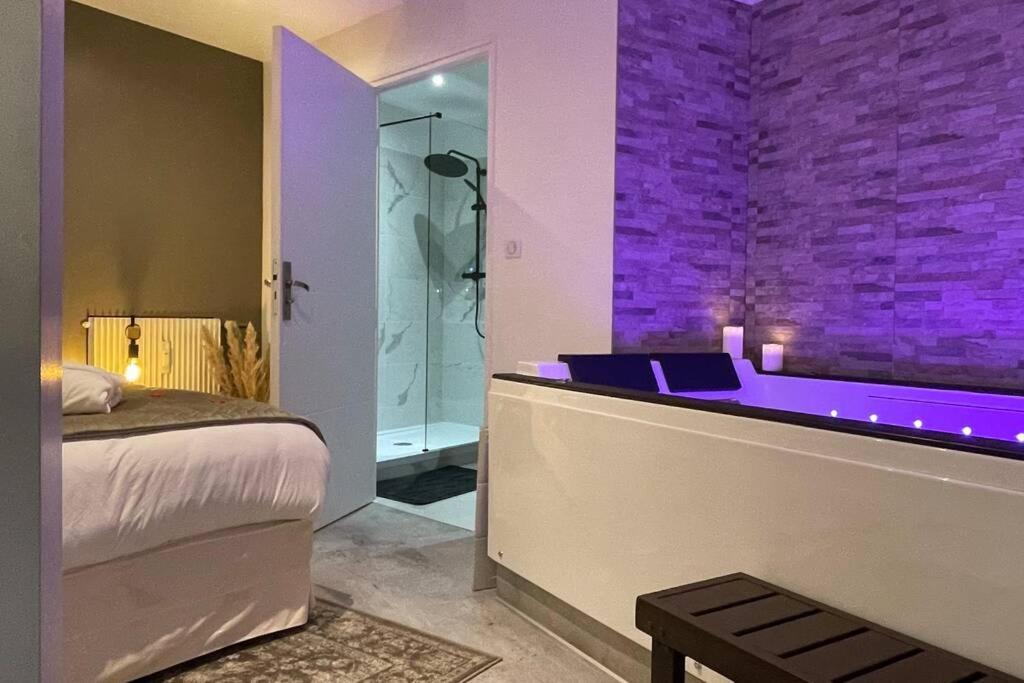 a bedroom with a tub with purple lighting at Appart&amp;Spa Devosge in Dijon