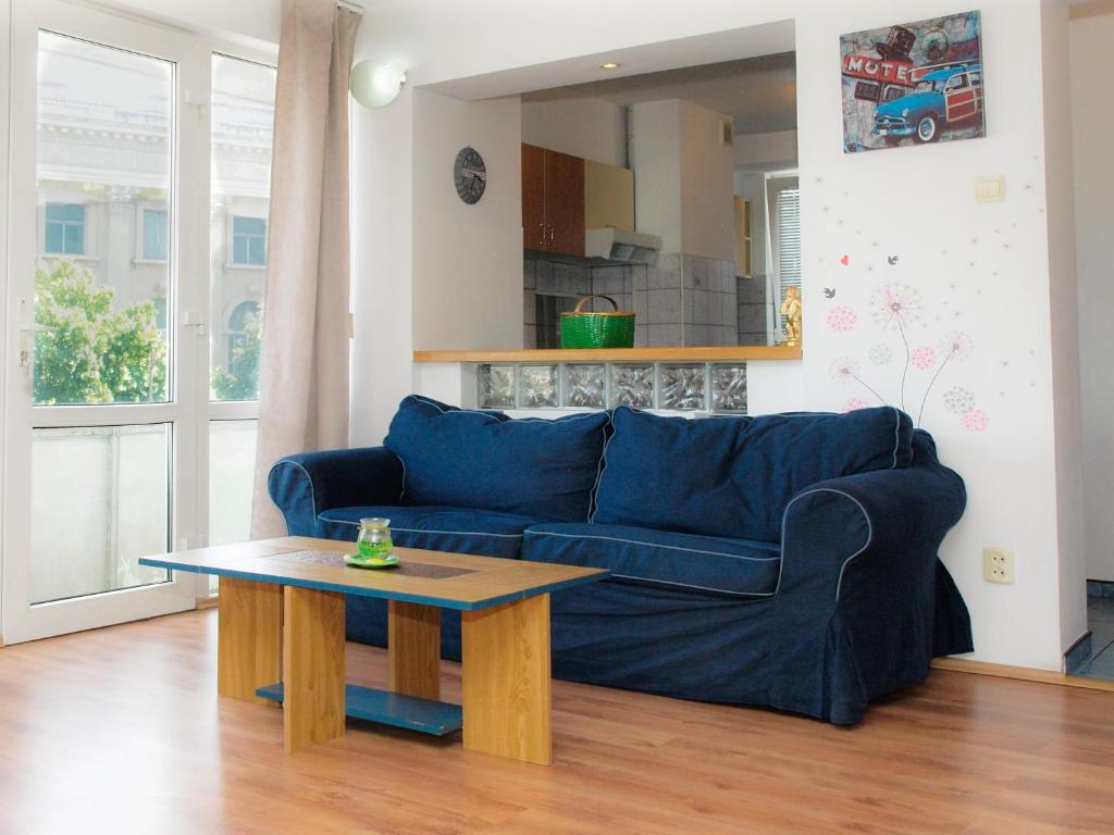 a blue couch in a living room with a table at Rosuites Apartment Accommodation in Bucharest