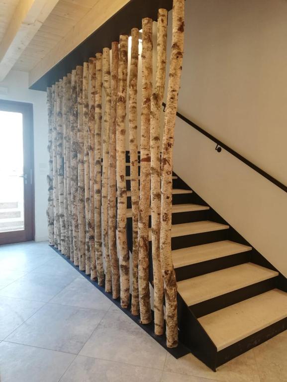 a staircase with a wall made out of tree branches at Crocevia - Locanda carsica contemporanea in Trieste