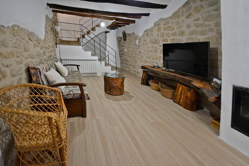 a living room with a television and a stone wall at Casa del Tio Vicente in Calaceite