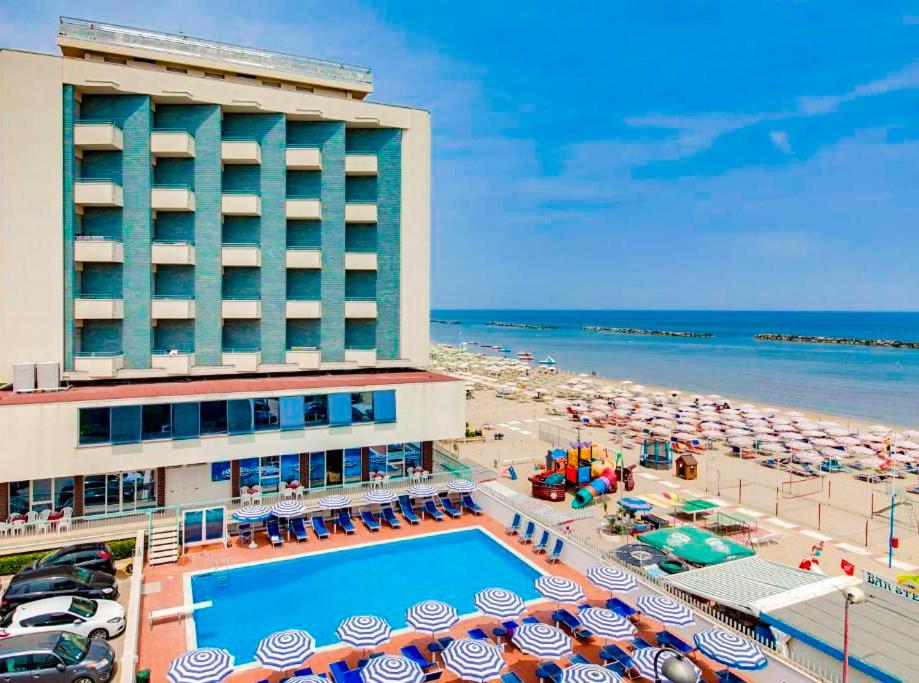 a hotel with a swimming pool and a beach with umbrellas at Hotel Majestic in Bellaria-Igea Marina