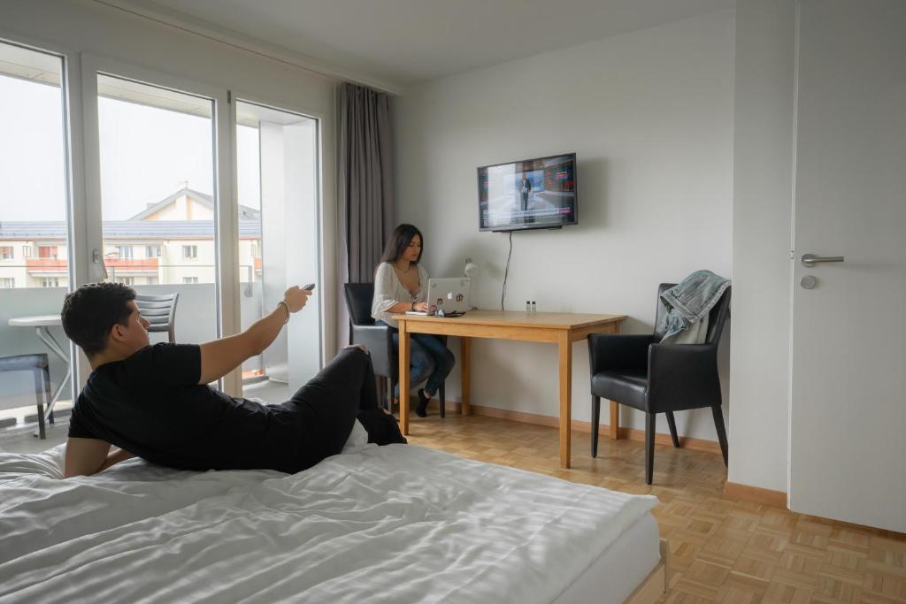 mężczyzna leżący na łóżku w pokoju hotelowym w obiekcie Nyon Hostel w mieście Nyon
