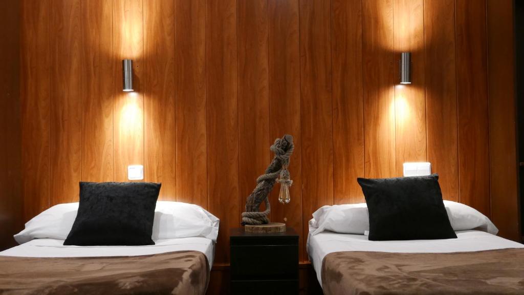 2 łóżka w pokoju hotelowym z drewnianymi ścianami w obiekcie Hostal Don Pedro w Madrycie