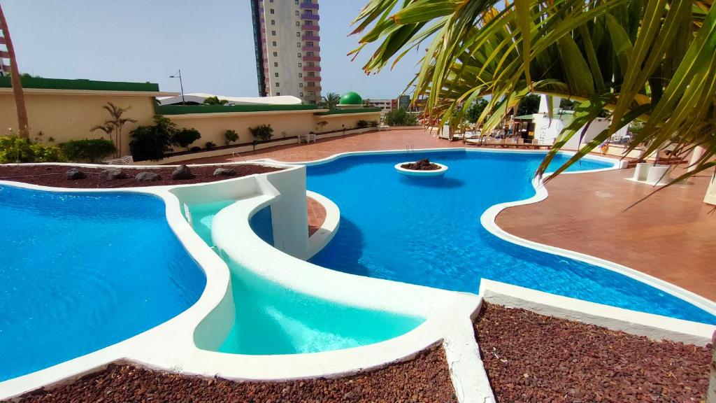 ein Swimmingpool in einem Resort mit blauem Wasser in der Unterkunft Natalia Beach Apartment in Adeje