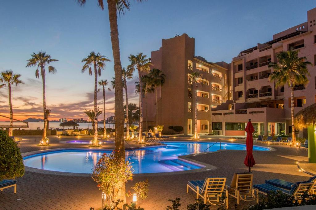 a swimming pool with palm trees and buildings at Marina Pinacate B-118 in Puerto Peñasco