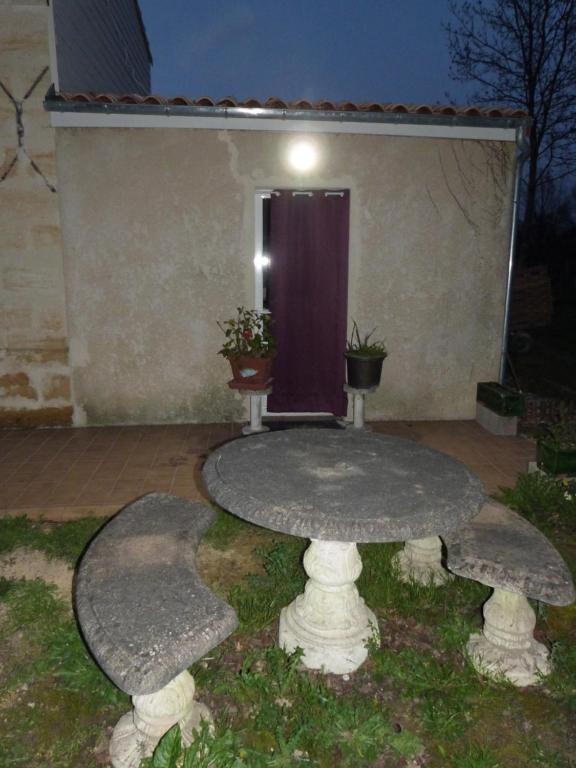 una mesa de piedra frente a una casa por la noche en la maison des coquelicots, en Saint-Genès-de-Fronsac