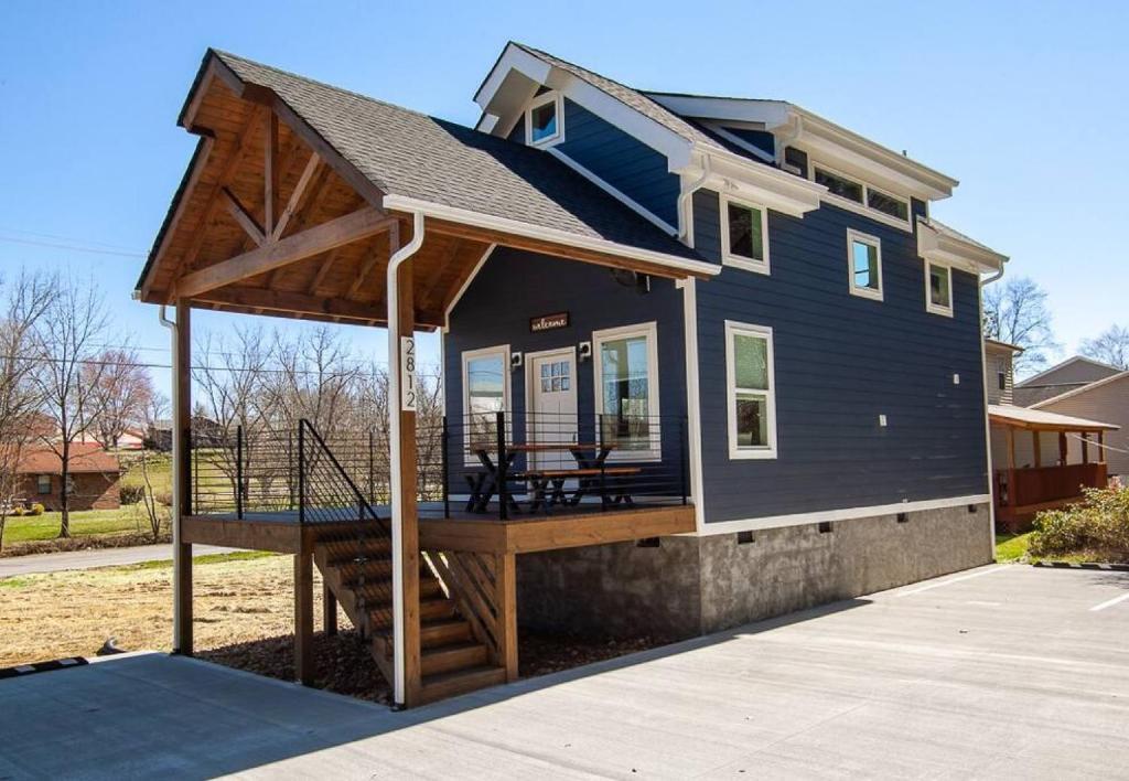 ein kleines blaues Haus mit einer Veranda und einer Terrasse in der Unterkunft Charming Smoky Mountain Tiny House in Pigeon Forge