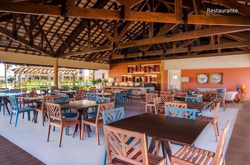 un restaurante con mesas y sillas en una habitación en VG Sun Cumbuco Bangalô E 201 adm Pessoa física en Cumbuco