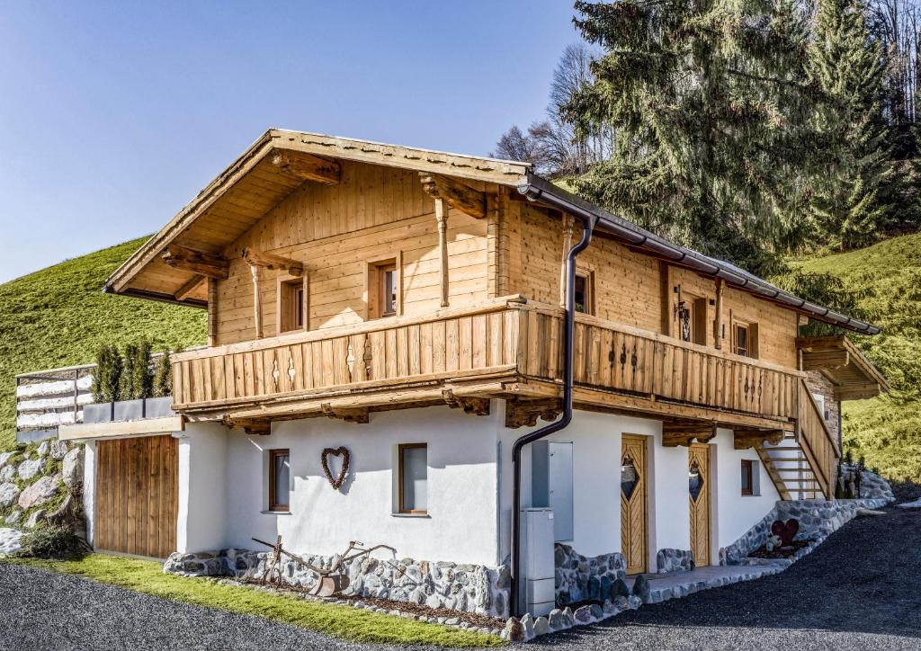 uma casa de madeira com uma varanda numa colina em Chalet Hüttenzauber em Kirchberg in Tirol