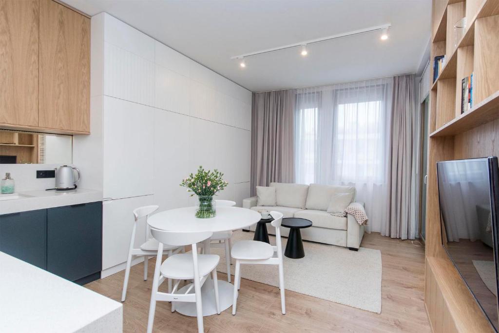 a kitchen and living room with a white table and chairs at Margo Rentyear Apartments in Gdańsk