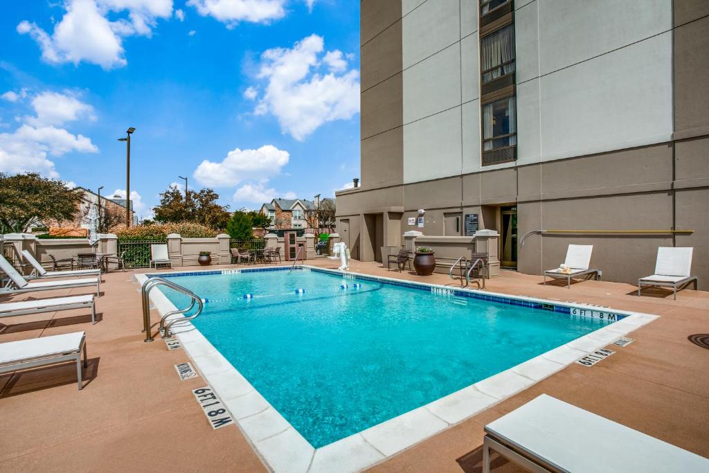 a swimming pool with chairs and a building at Hyatt Place Fort Worth/Hurst in Hurst