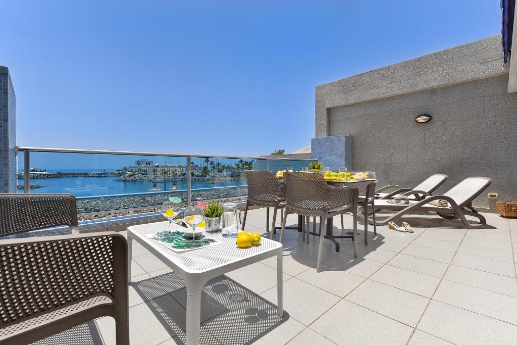 a patio with a table and chairs on a balcony at Luxury BeachFront Mogan in Puerto de Mogán