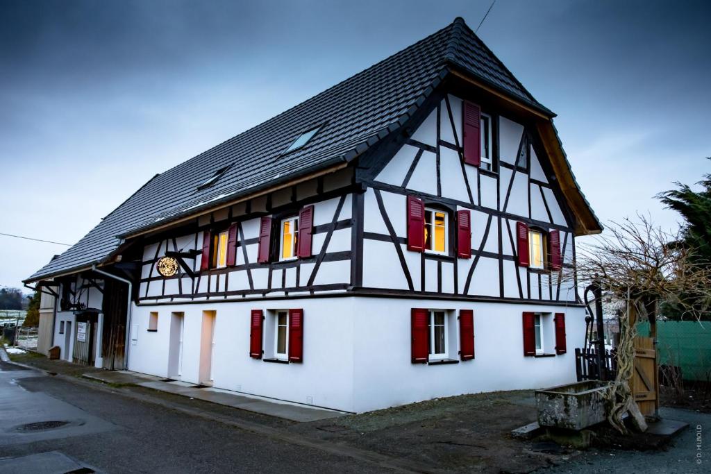 un bâtiment blanc et noir avec un toit noir dans l'établissement Gîte Les Sabots de Paille, Alsace Haut-Rhin, à Ballersdorf