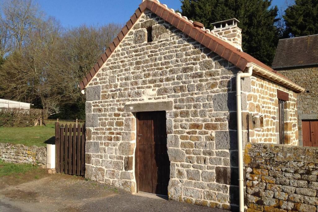 a small brick building with a brown door at La Cahute in La Forêt-Auvray