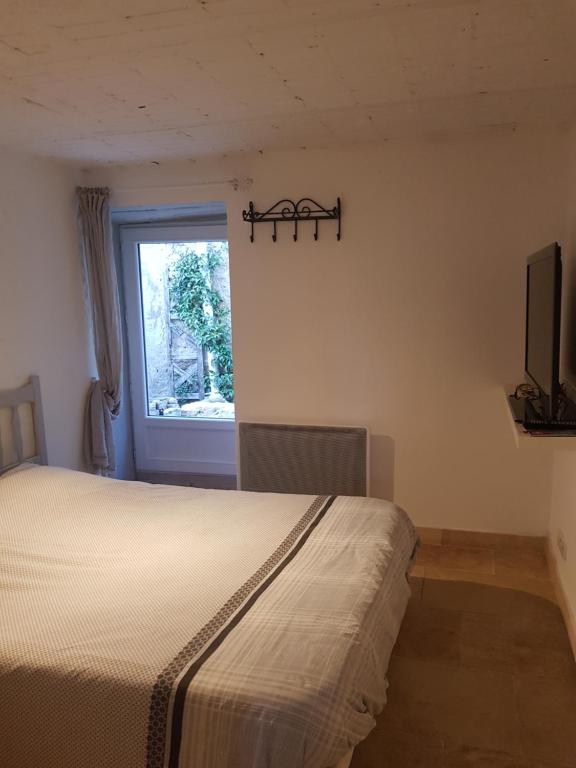 een slaapkamer met een bed en een raam bij Chambre d'hôte Geiko in Cabrières-dʼAigues