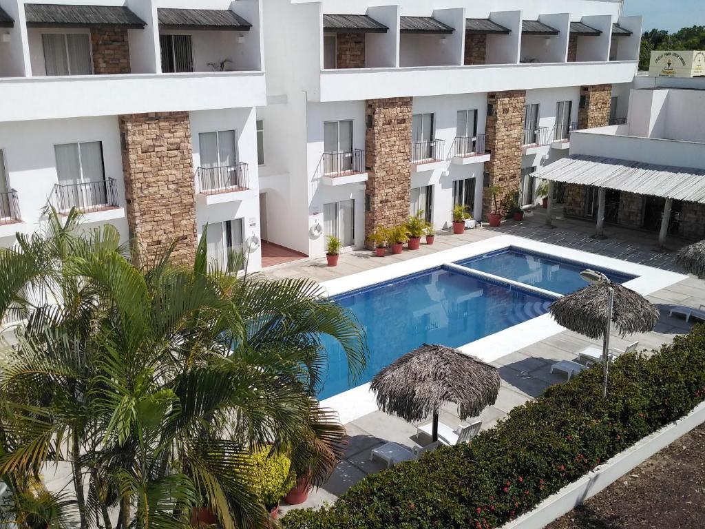 an image of a building with a swimming pool and palm trees at La Mansión del Faro in Tecolutla