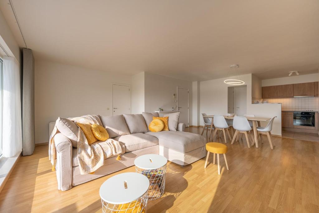 a living room with a couch and tables and a kitchen at Meerzicht-Laguna in Knokke-Heist