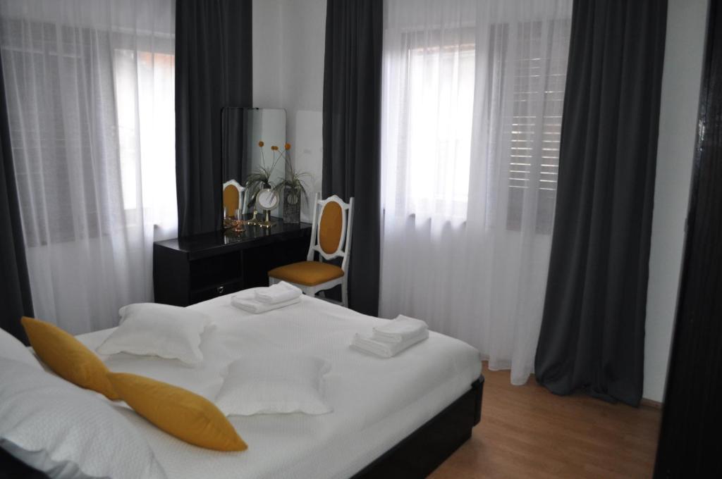 a bedroom with a bed with white sheets and a chair at La Pausa suite Prijepolje in Prijepolje