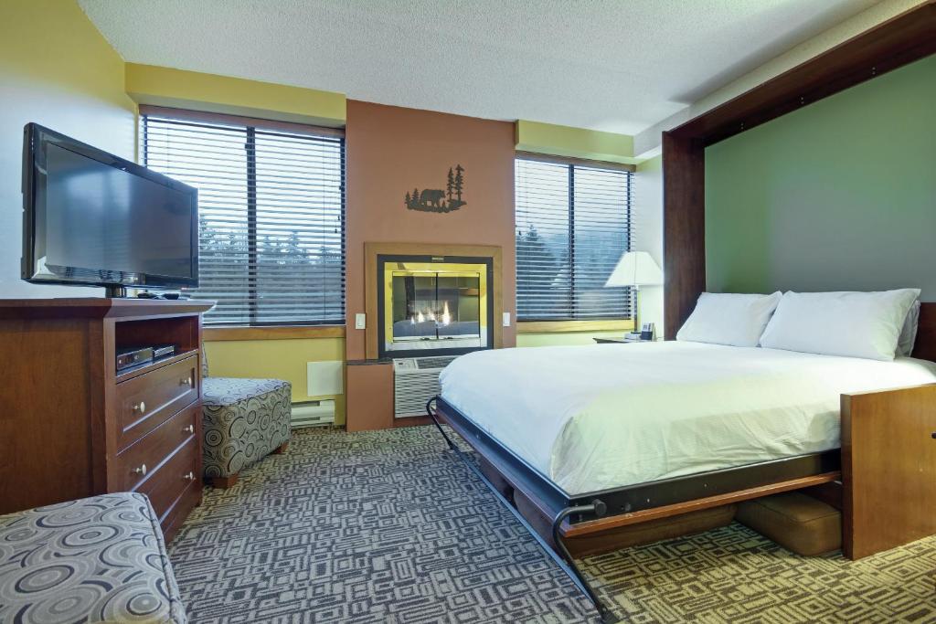 um quarto de hotel com uma cama e uma televisão de ecrã plano em Mountainside Lodge em Whistler