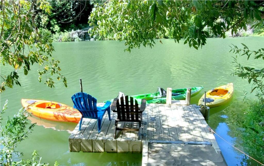 a dock with chairs and boats on a lake at Reflections! Seasonal Dock & Kayaks!! Hot Tub!! Fire Table! BBQ! HUGE yard! Horseshoes! Dog Friendly! in Guerneville