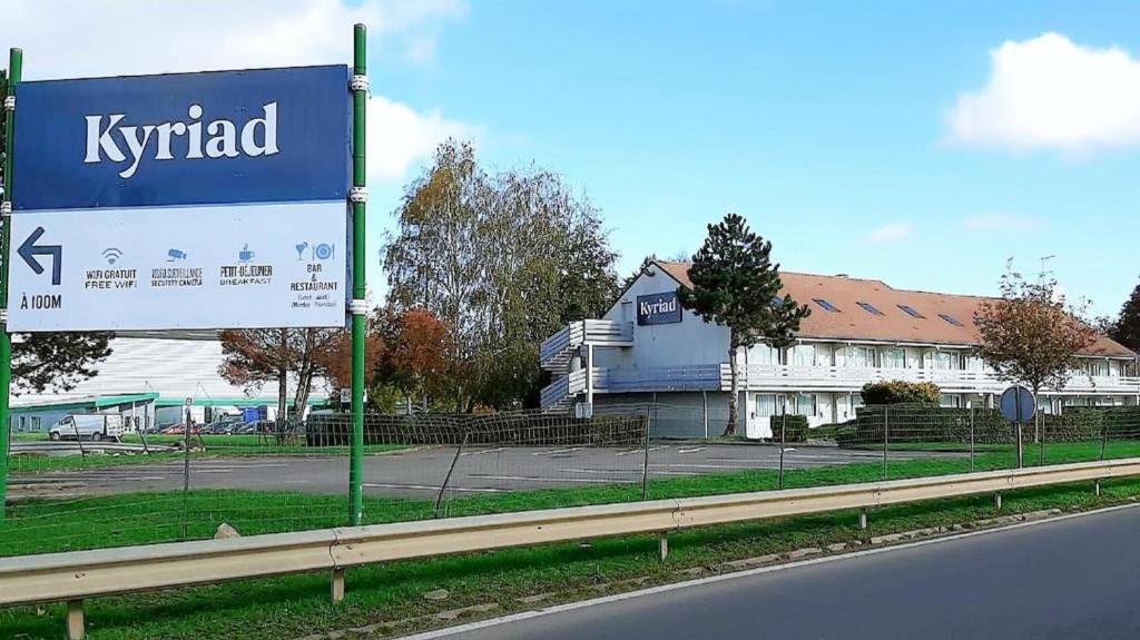 a sign on the side of a road next to a building at Kyriad Cambrai in Cambrai