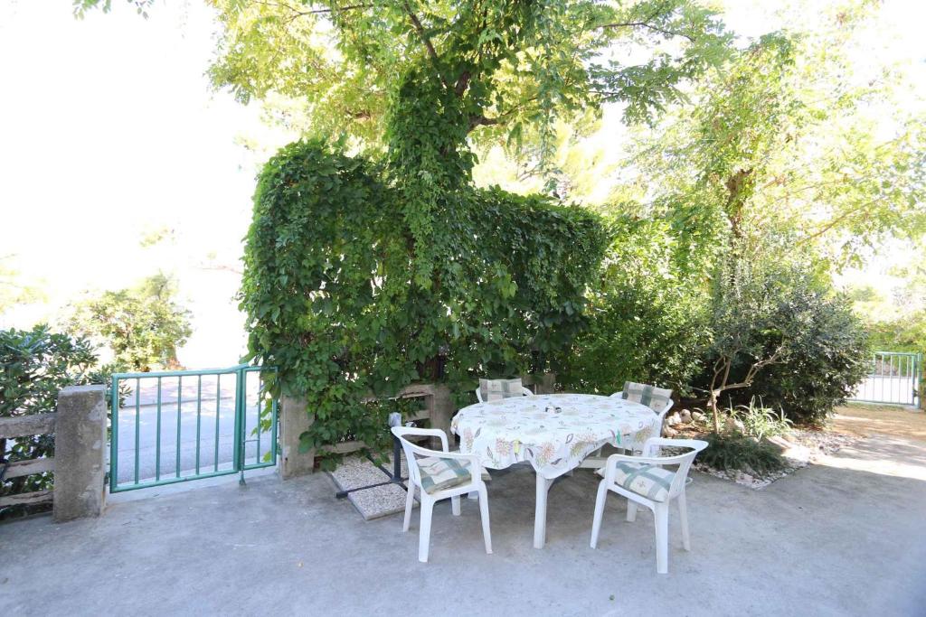 un tavolo bianco e sedie seduti sotto un albero di Apartment Silo 19 a Šilo