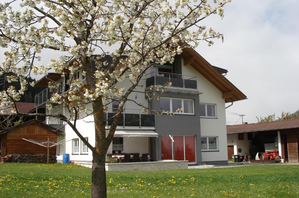 una casa con un árbol delante de ella en Ferienwohnungen Simon - Hauserhof, en Oberperfuss