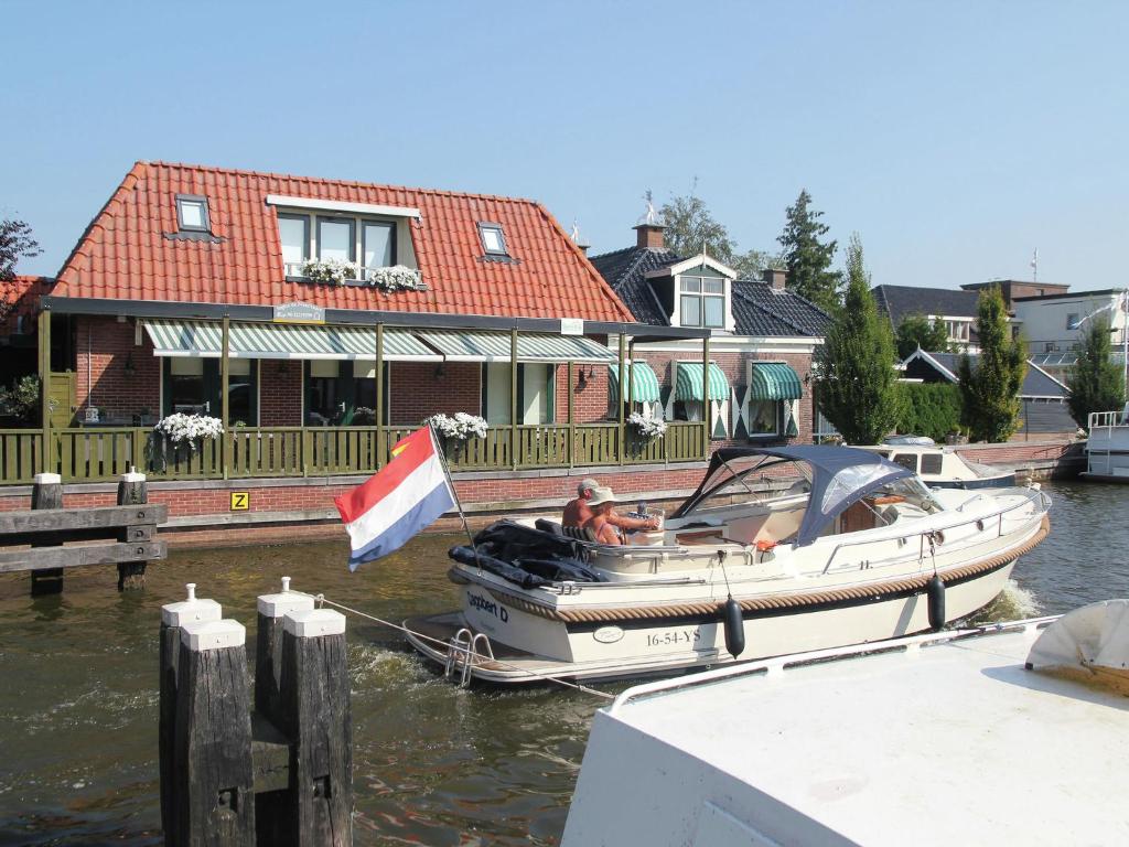 un petit bateau amarré à un quai avec une maison dans l'établissement Unique Holiday Home with Terrace Barbecue Garden Furniture, à Delfstrahuizen