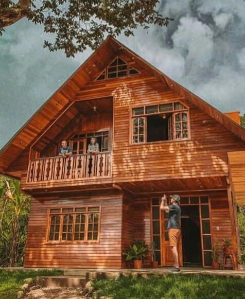 a man standing in the doorway of a wooden house at La Cabaña de Noa in Oxapampa