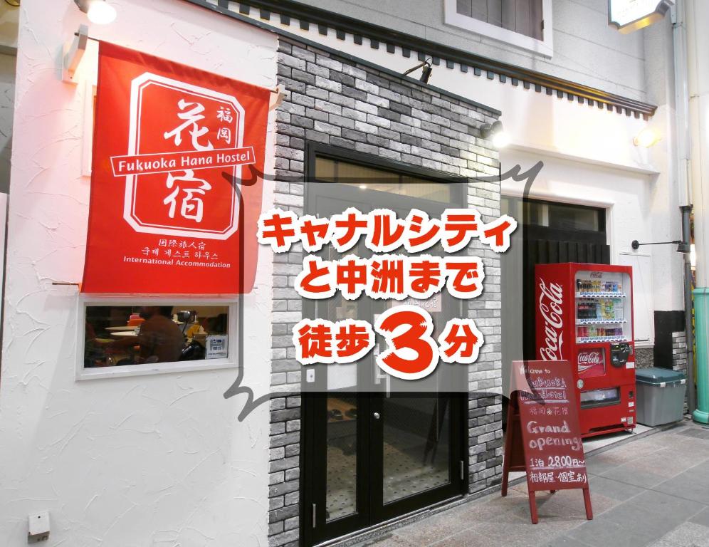 een winkel met borden aan de zijkant van een gebouw bij Fukuoka Hana Hostel in Fukuoka