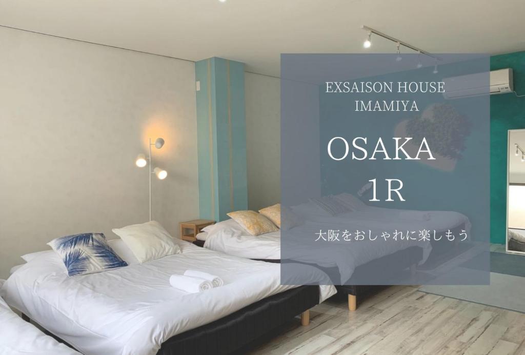 - 2 lits dans une chambre avec un mur bleu dans l'établissement Ex2 House Imamiya 202, à Osaka
