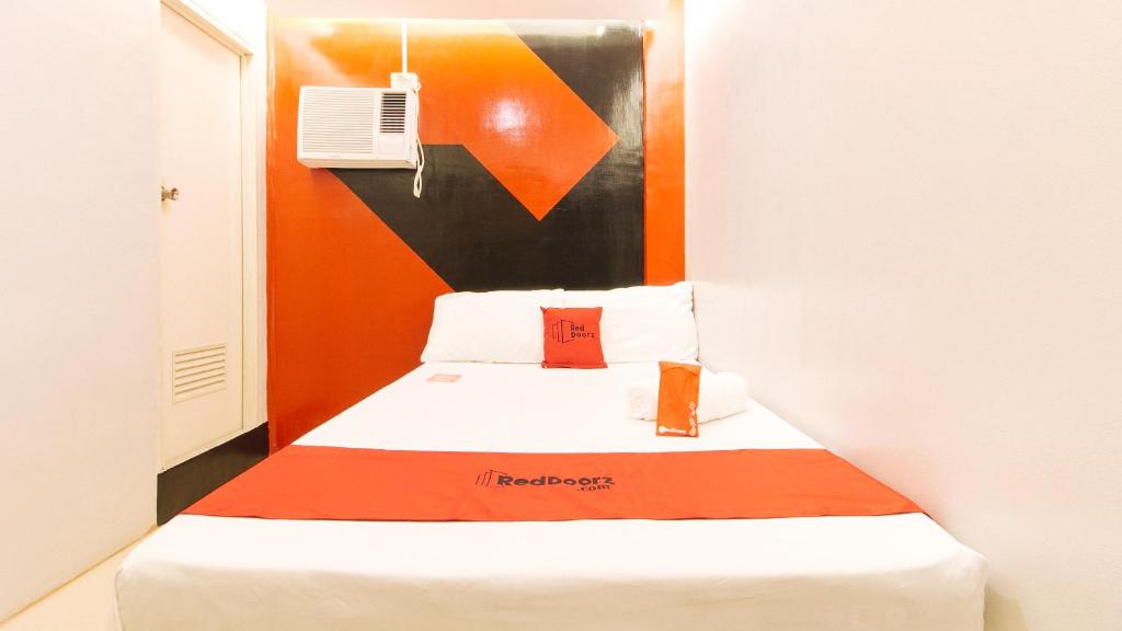 um pequeno quarto com uma cama com cabeceira laranja em RedDoorz @ Walk Inn Hotel em Manila
