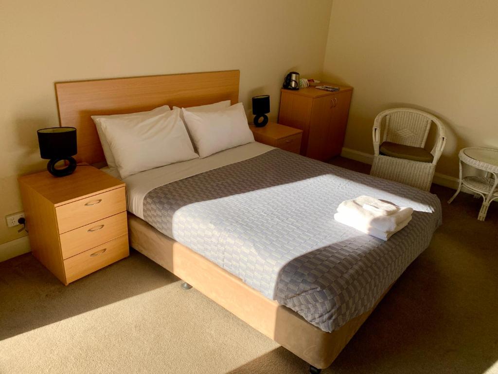 a bedroom with a bed and two tables and a chair at Settlers Hotel York in York