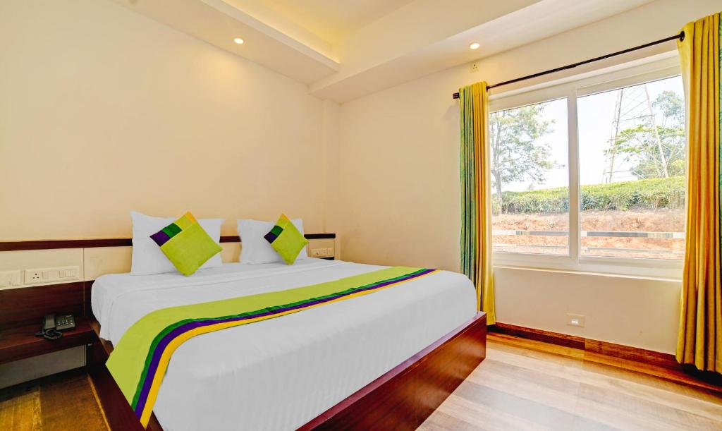 a bedroom with a large bed and a window at Treebo Trend Wanderlust Residency With Mountain View in Munnar