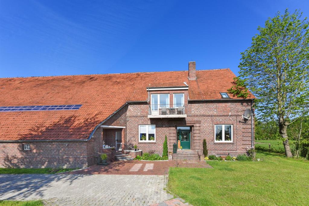 een stenen huis met een rood dak bij Ferienwohnungen auf dem Ferienhof an der Schafweide in Werdum