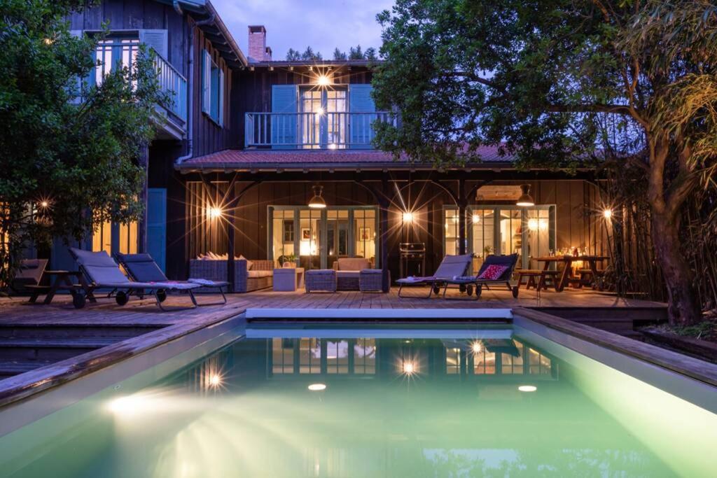 una casa con piscina di fronte a una casa di La Villa du Phare - 240 m² avec 5 chambres piscine a Lège-Cap-Ferret
