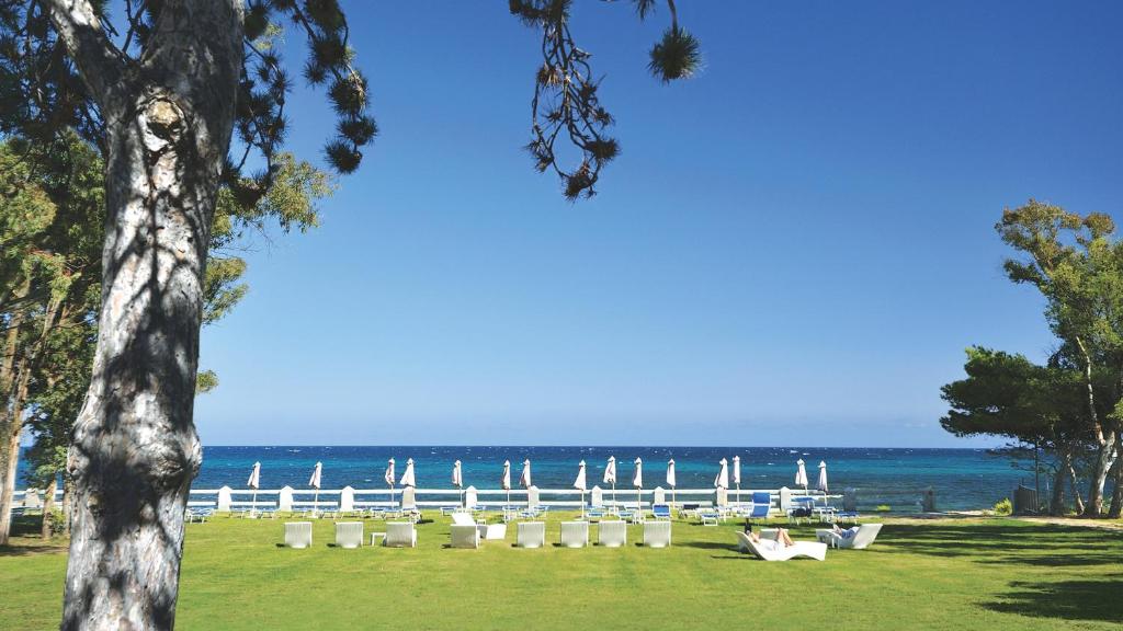 a park with chairs and the ocean in the background at SECRET VILLAGE Budoni in Budoni