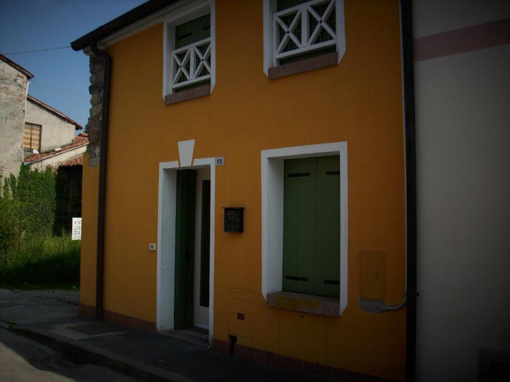 een geel gebouw met een groene deur en twee ramen bij Appartamento Sonia in Thiene