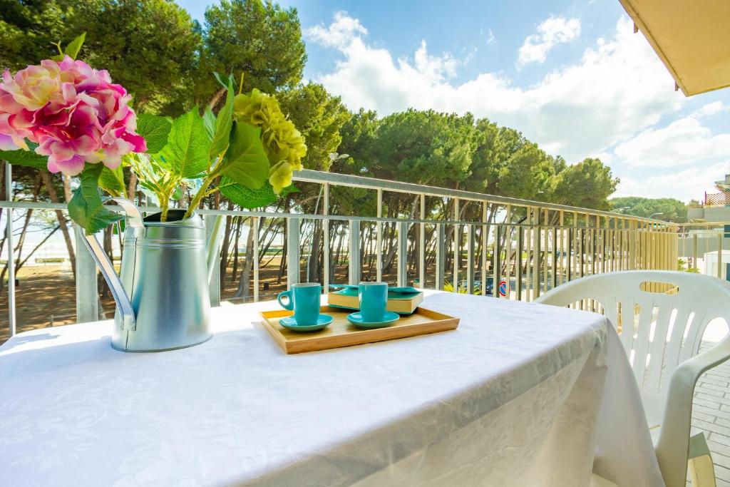 einen weißen Tisch mit einer Vase mit Blumen drauf in der Unterkunft Appartamento Il Timone 1 Piano - MyHo Casa in Alba Adriatica