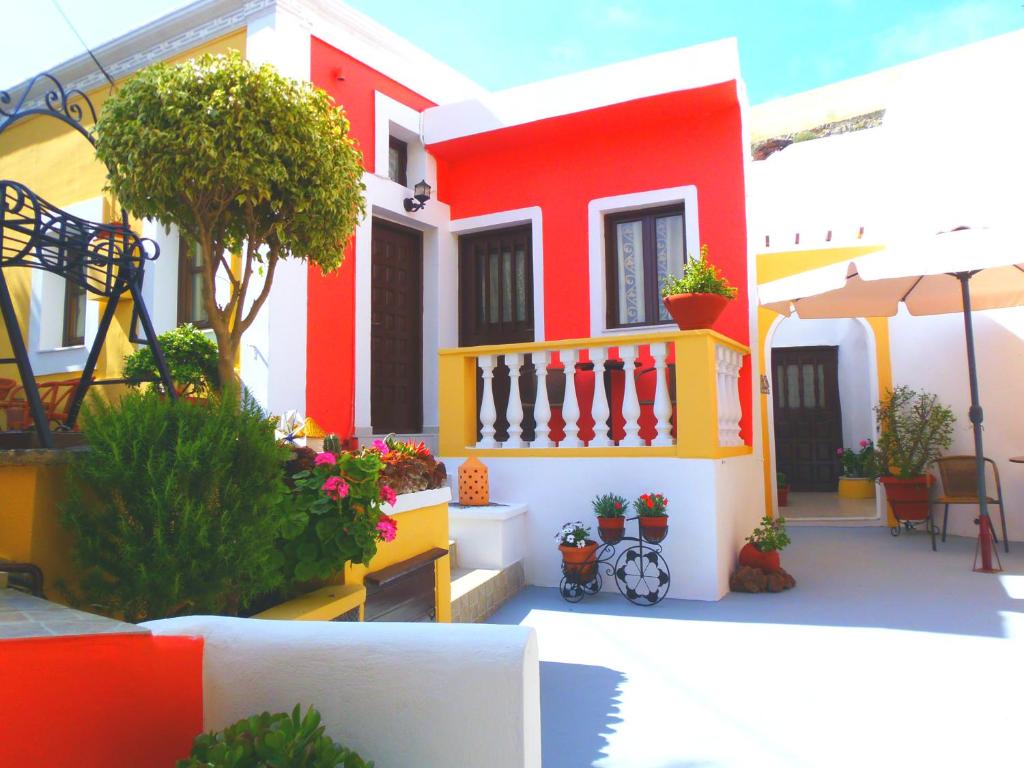 a red and white house with flowers and plants at Pansion Zaharoula in Fira
