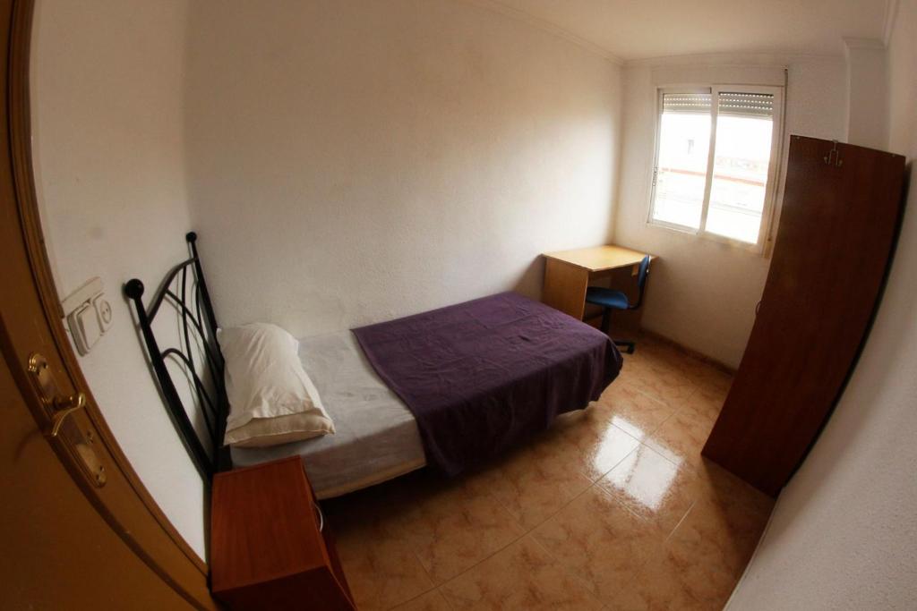 Habitación pequeña con cama y ventana en apartemento ideal grupo y familia climatisacion y cerca playa . mongrell, en Valencia