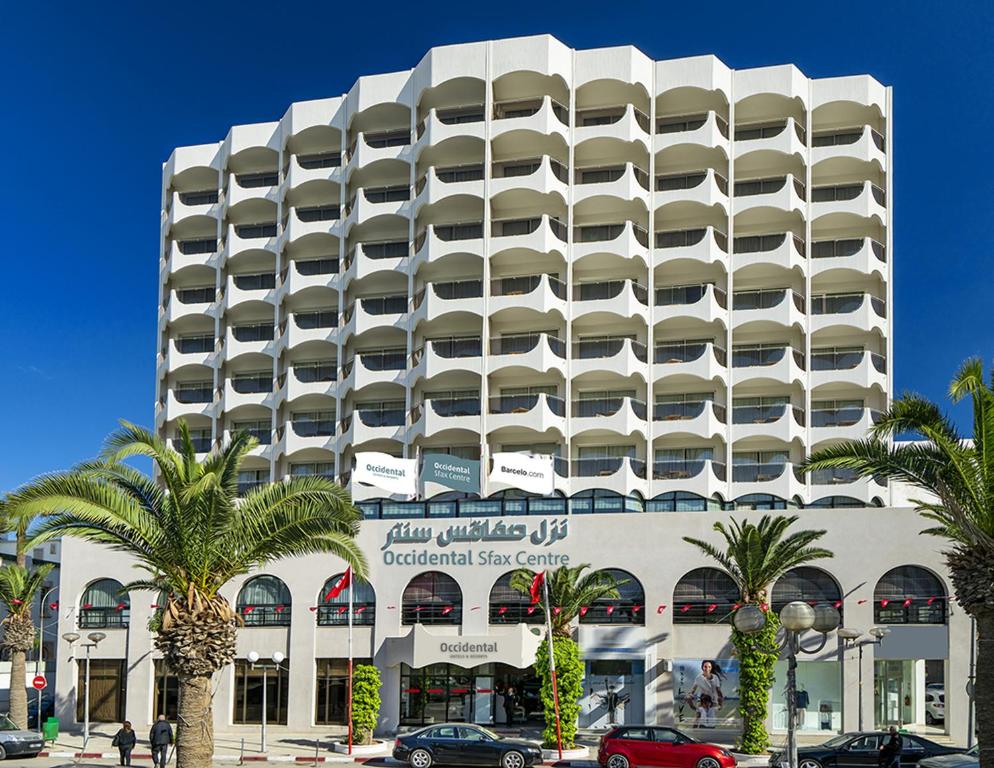 斯法克斯Concorde Sfax Centre的一座巨大的白色建筑，前面有棕榈树