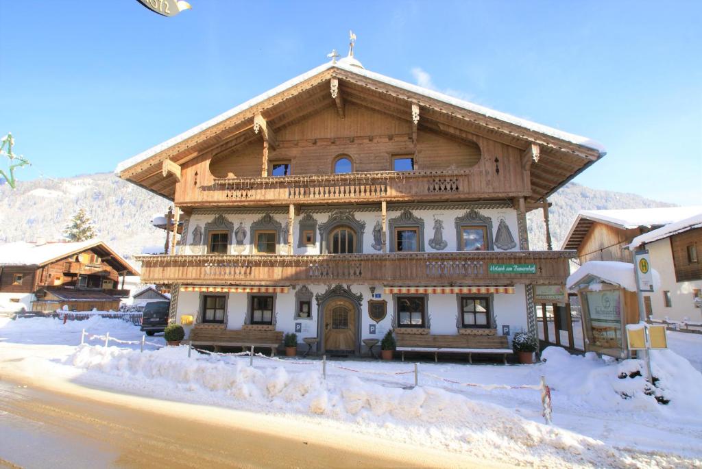 un gran edificio de madera con nieve en el suelo en All Inclusive Hotel Bachmayerhof en Uderns