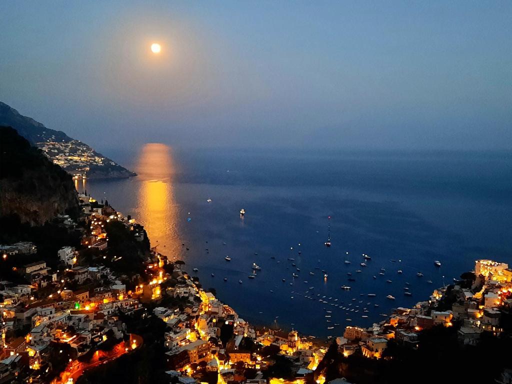 a full moon rising over a city and the ocean at La casa del Capitano B&b in Positano