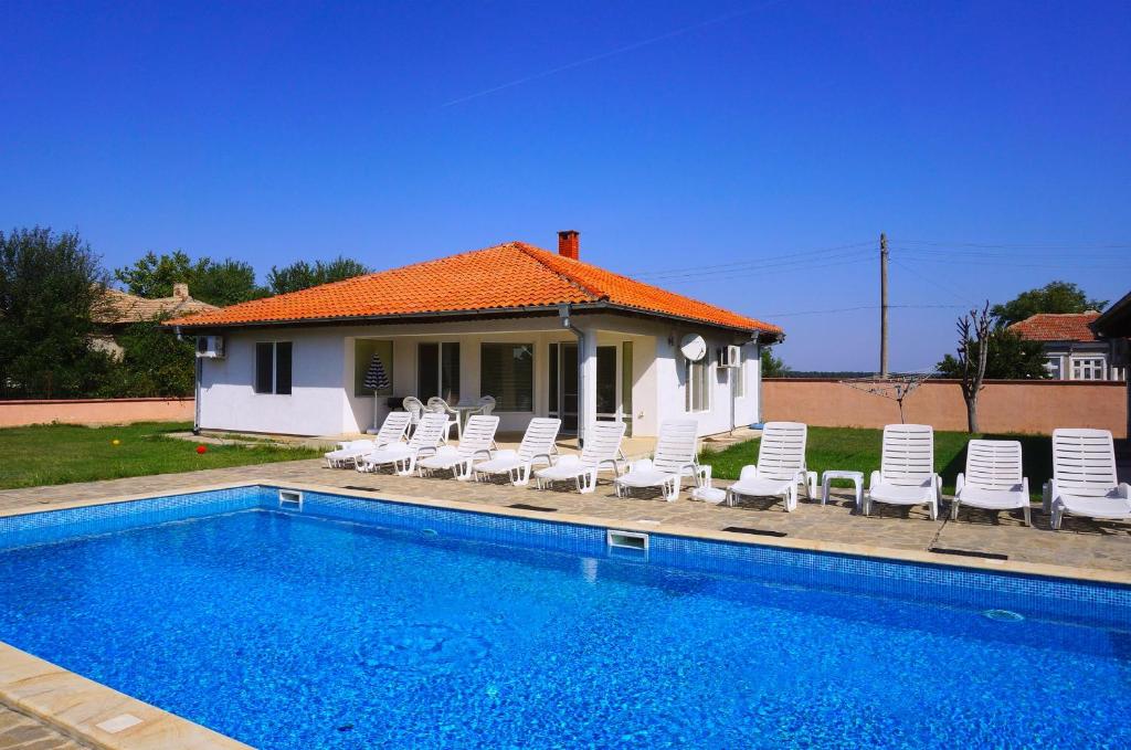 - une piscine avec des chaises et une maison dans l'établissement Вили Брендън и Дезмънд - до Балчик - Brendon and Desmond Villas - near Balchik, à Sokolovo