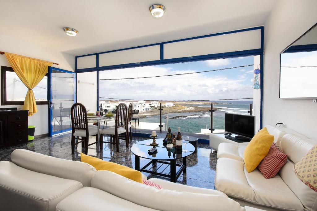 a living room with white furniture and a large window at Vista Mejía 1 in Caleta de Caballo