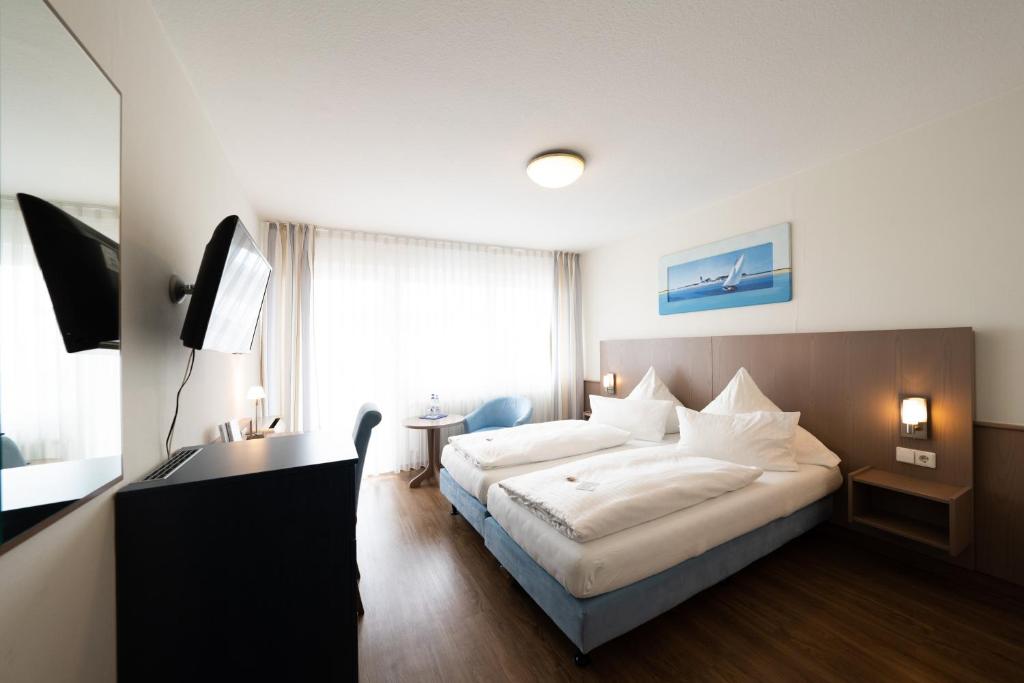 a bedroom with a bed and a desk and a television at ates Hotel Kehl in Kehl am Rhein