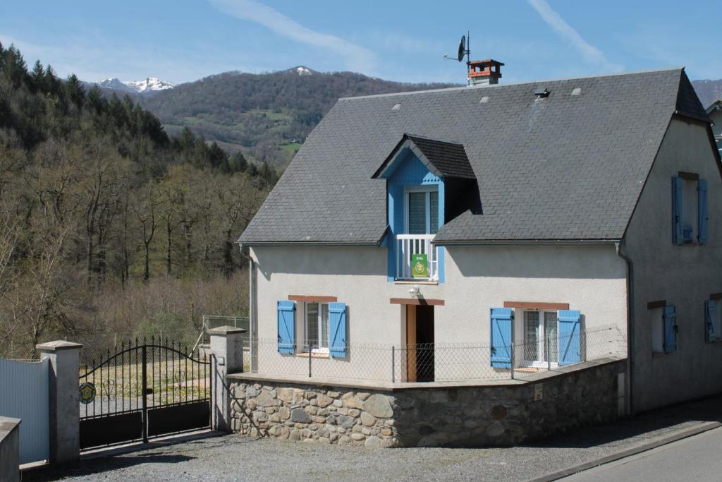 Casa blanca con ventanas azules y valla en Gite Ladagnous, en Peyrouse