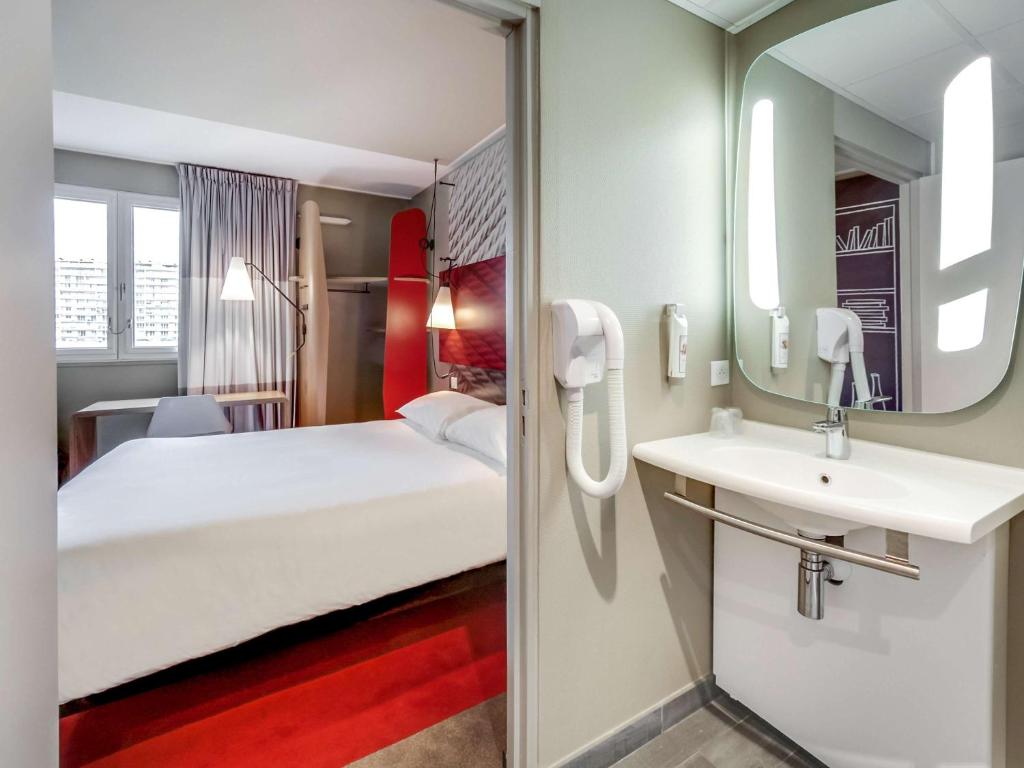 a bedroom with a bed and a sink and a mirror at ibis Orleans Centre Gare in Orléans